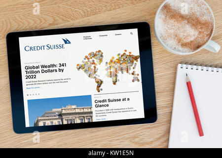 Le Credit Suisse Site internet sur une tablette iPad, reposant sur une table en bois à côté d'un bloc-notes, crayon et tasse de café (rédaction uniquement) Banque D'Images