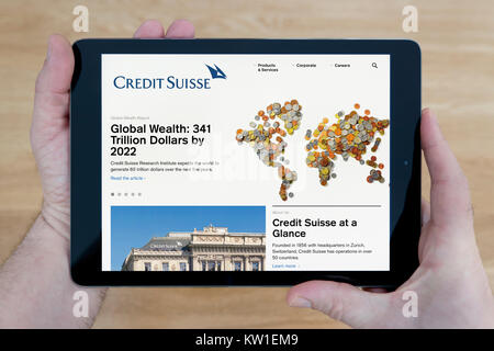 Un homme se penche sur le site de la banque Crédit Suisse sur son iPad tablet device, tourné contre une table en bois page contexte (usage éditorial uniquement) Banque D'Images