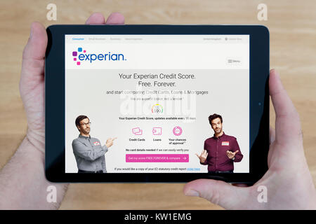 Un homme regarde le site d'Experian sur son iPad tablet device, tourné contre une table en bois page contexte (usage éditorial uniquement) Banque D'Images
