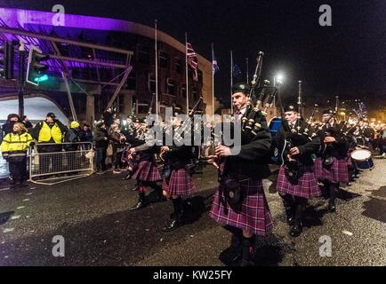 Edinburgh, Royaume-Uni. Dec 30, 2017. Edinburgh Hogmanay du début des célébrations avec la traditionnelle procession aux flambeaux. Cette année, la route se termine à l'extérieur du Parlement écossais à Holyrood où un mot choisi par les jeunes de l'Écosse qui les rend fiers de vivre dans le pays se révèle par les milliers de porteurs. Sur la photo : Pipe Band menant la procession aux flambeaux devant le Parlement écossais Credit : Riche de Dyson/Alamy Live News Banque D'Images