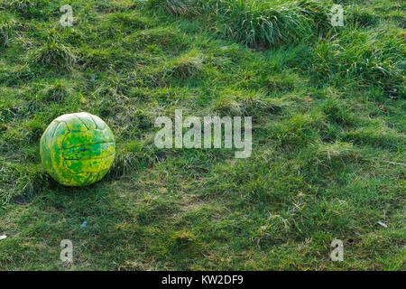 Close up d'un football en cuir vert/jaune assis dans un parc sur une herbe verte sur une journée ensoleillée d'automne. Banque D'Images