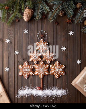 À partir de l'arbre de Noël gingerbread stars avec la neige autour sur fond brun rustique Banque D'Images