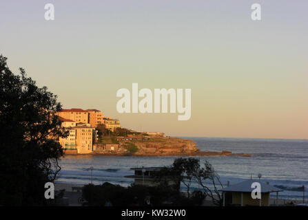 La photo capture Bondi Beach en Australie pendant la lumière du soir, mettant en valeur la beauté sereine de la plage, ses vagues emblématiques, et l'atmosphère tranquille alors que le jour passe à la nuit. Banque D'Images