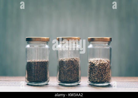 Sweet cumin, cumin blanc et les graines de coriandre dans un bocal en verre sur une table en bois Banque D'Images