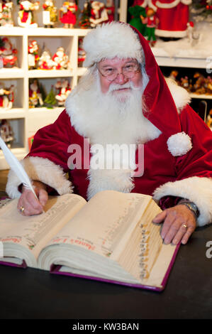 USA Virginia VA Williamsburg le Père Noël Le Père Noël Saint Nicolas assis sur sa chaise dans son atelier faire une liste dans son livre Banque D'Images