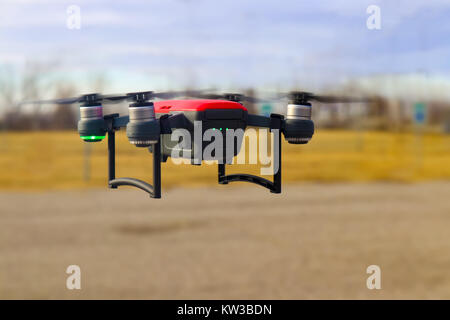 Petit rouge et gris Drone en vol avec trois quarts contre charge batterie arrière-plan flou - hiver Banque D'Images