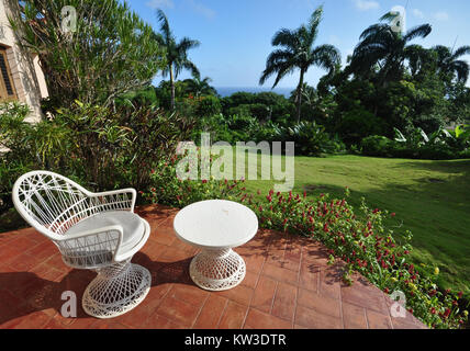 Jardin patio à resort en République Dominicaine vous offre une retraite paisible. Siège en osier blanc et rouge sur la table entourée de carreaux en terre cuite Banque D'Images