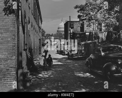 Les gens se promènent à travers cour du temple sur des rues pavées sur lesquelles une file de voitures est garée, à Washington, D.C, Washington, DC, 1940. À partir de la Bibliothèque publique de New York. Banque D'Images