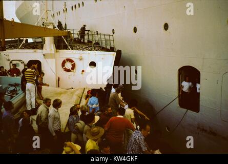 Les touristes à se préparer à descendre d'une porte sur la ligne Cunard Queen Elizabeth 2 navire de croisière sur un petit bateau qui a tiré à côté, en mer, 1975. Banque D'Images