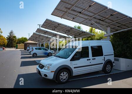 Au Googleplex, siège de l'entreprise moteur de recherche Google dans la Silicon Valley ville de Mountain View, Californie, un petit fourgon électrique est garée à l'ombre d'un panneau solaire qui alimente une station de charge pour le van, avec d'autres stations de recharge et les véhicules électriques visibles dans l'arrière-plan, Mountain View, Californie, le 24 août 2016. Banque D'Images