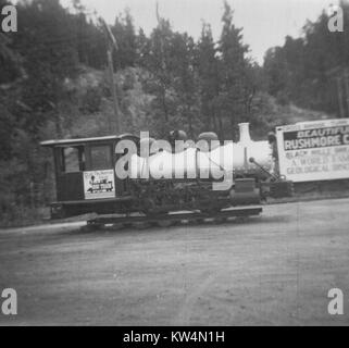 Locomotive à voie étroite sur l'affichage à l'extérieur de l'établissement Mount Rushmore, avec un signe dans l'arrière-plan la Montagne de la publicité, le Dakota du Sud, 1950. Banque D'Images