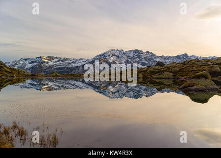 Lac alpin de haute altitude dans un paysage idyllique. Reflet de snowcapped mountain range et panoramique ciel coloré au coucher du soleil. Prise de vue au grand angle pris sur la th Banque D'Images