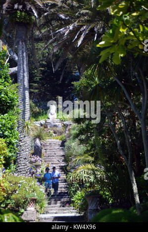 Un couple en train de marcher sur les marches de pierre de la statue de Neptune sur le phare à pied dans les jardins de l'abbaye de Tresco, Îles Scilly, Angleterre, Cornwall, UK. Banque D'Images