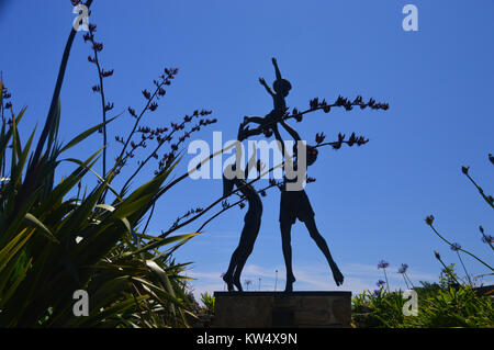 Silhouette de la sculpture en bronze de David Wynne de trois enfants jouant dans Tresco Abbey Gardens, Tresco, Îles Scilly, Cornwall, UK. Banque D'Images