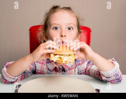 Petite fille émotionnellement mange un sandwich Banque D'Images