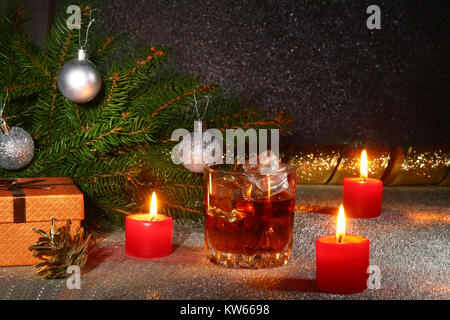 Décoration de Noël avec verre de whisky ou de cognac, bougies de Noël, arbre et boîte-cadeau sur une magnifique arrière-plan. Décoration Nouvel An. Banque D'Images