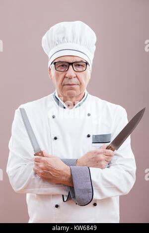 Le chef du restaurant de portrait en uniforme de travail tenant des couteaux de cuisine Banque D'Images