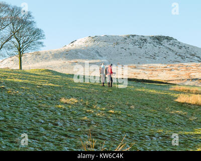 L'homme et la femme marche dans la neige au pied d'Shutlingsloe Hill and Wildboarclough Peak District le 3e plus haut sommet dans Cheshire Banque D'Images