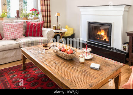 Intérieur salon avec cheminée, deux canapés, tapis rouge, une table basse en bois sur un plancher en chêne. Banque D'Images