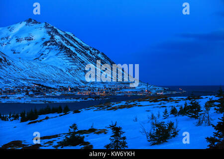 Belle vue sur Siglufjordur au crépuscule en hiver. Siglufjordur est un petit village de pêcheurs dans un fjord étroit sur la côte nord de l'Islande. Banque D'Images