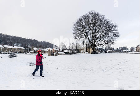 Une femme marche dans la neige à Hutton-le-Hole partie de la North York Moors National Park. Banque D'Images