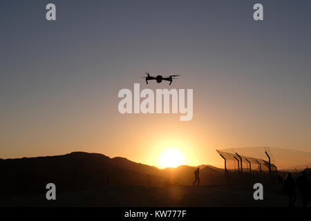 Un appareil radio controlled quadcopter drone survolant la silhouette d'un homme qui court à une position de défense de l'armée israélienne sur une colline stratégique dans l'ouest de la vallée de la plaine connue en hébreu comme Arava ou Aravah qui fait partie de la frontière entre Israël et la Jordanie. Banque D'Images