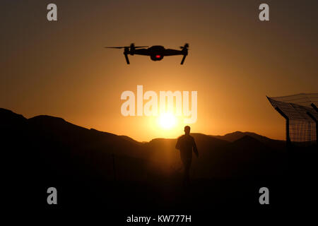 Un appareil radio controlled quadcopter drone survolant une silhouette d'homme debout à une position de défense de l'armée israélienne sur une colline stratégique dans l'ouest de la vallée de la plaine connue en hébreu comme Arava ou Aravah qui fait partie de la frontière entre Israël et la Jordanie. Banque D'Images