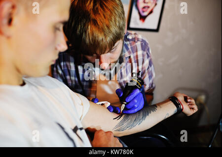 Tatoueur fait un nouveau tatouage pour un jeune mec Banque D'Images