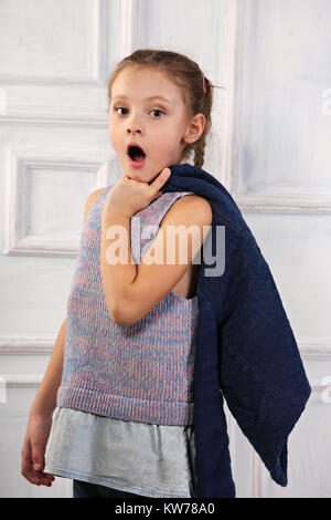 Surprenant kid girl avec bouche ouverte à la recherche et à la tenue veste bleue. Closeup portrait Banque D'Images