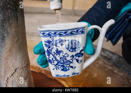 Main dans la main une tasse de remplissage avec de l'eau minérales thérapeutiques lors d'une source chaude naturelle dans la région de Karlovy Vary en hiver, en République Tchèque Banque D'Images