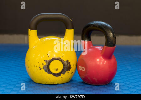 Le rouge et le jaune utilisé et vieux kettlebells sur fond bleu. Appareils d'entraînement Banque D'Images