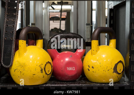 Jeu de colorful usé kettlebells sur une étagère métallique dans une salle de sport. Banque D'Images