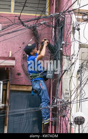 Un électricien travaillant sur une masse de câbles aériens, Cebu City, Philippines Banque D'Images