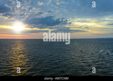 Paysage pittoresque sur la mer - le soleil se lève sur la mer contre un ciel nuageux et dans la distance que vous pouvez voir le navire et la terre. Banque D'Images