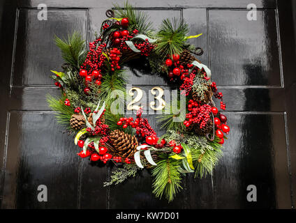 Couronne décorative de Noël sur la porte d'entrée de la maison de ville géorgienne, Edinburgh New Town, Écosse, Royaume-Uni, avec le numéro de laiton 23 sur la porte à panneaux noirs Banque D'Images