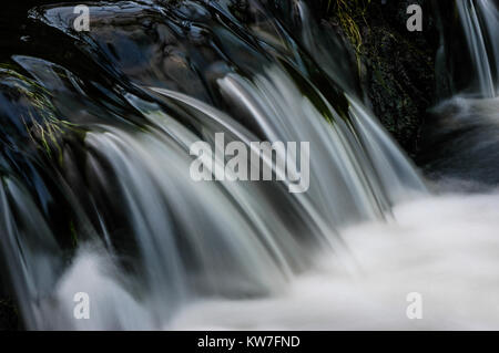 La rivière Dove circulant sur un petit barrage de la vallée boisée de Beresford Dale dans le parc national de Peak District, England, UK Banque D'Images