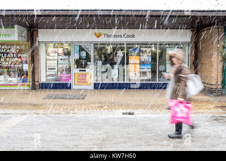 Femme marche passé extérieur de la succursale de l'agence de voyage Thomas Cook en hiver neige Banque D'Images