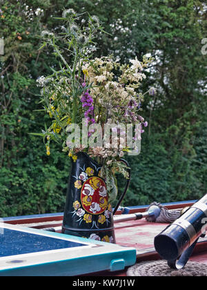 Bouquet de fleurs sauvages dans un canalware verseuse en métal peint avec des roses Banque D'Images