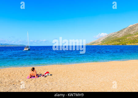 De jeune touriste de bronzer sur une plage de Zlatni Rat (Corne d'or) avec une vue magnifique sur la mer, l'eau la plus célèbre plage de la mer Adriatique, l''île de Brac Banque D'Images