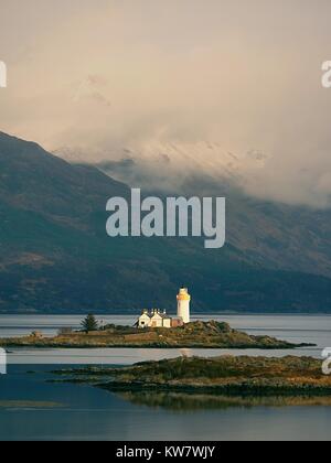 Isle Ornsay avec blanc tour de phare, île de Skye, en Écosse. Journée d'hiver ensoleillée avec les montagnes enneigées en arrière-plan. Banque D'Images