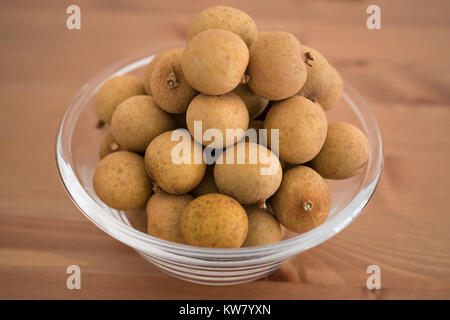 Bol rempli avec un heap Dimocarpus Longan fruits isolés sur fond de bois Banque D'Images