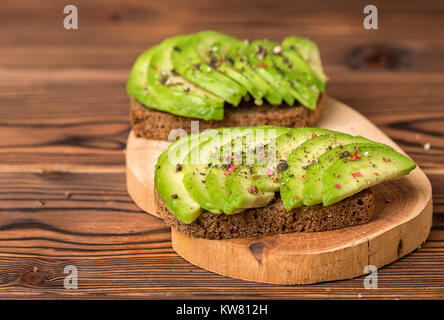 L'avocat des sandwichs avec du pain de seigle coupées et saupoudrer de poivre sur fond de bois, d'une saine alimentation Banque D'Images