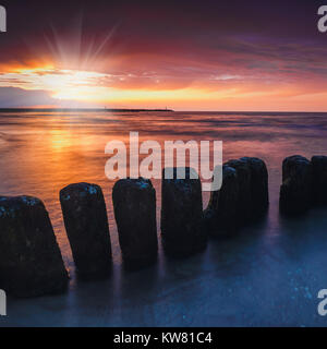 Coucher du soleil sur la plage avec un brise-lames en bois, long exposure Banque D'Images