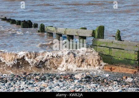 La marée et les vagues ayant leur énergie dissipée par le brise-lames en bois sur la plage de sable et de galets à la station balnéaire de Cleveleys Banque D'Images