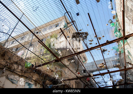 Hébron, en Palestine, le 7 novembre 2010. Barrière de barbelés et filet rempli de pierres et d'ordures installé entre zone occupée et Palestinia Banque D'Images