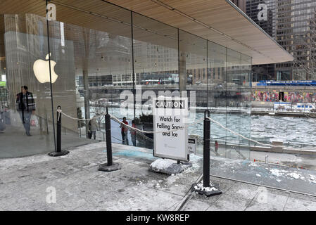 Chicago, USA. 31 décembre 2017. Des panneaux de mise en garde les passants par des chutes de glace sont à l'écran autour de la nouvelle figure de proue des Apple Store, North Michigan Avenue, à côté de la rivière Chicago. Le bâtiment, conçu par les architectes britanniques Foster +Partners, possède un toit en forme le couvercle d'un portable Apple et s'affiche à l'absence visible des gouttières. Les glaçons qui se sont formées dans l'actuelle des températures sous zéro se sont écrasés au sol ci-dessous mettant en danger le public et le magasin est actuellement confronté à des critiques de la part des sections locales à élaborer une solution. Crédit : Stephen Chung / Alamy Live News Banque D'Images