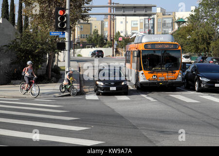 Mère et enfant à vélo pour attendre le bus et la circulation pour traverser la route aux feux de circulation sur l'Avenue Rowena Silver Lake, Los Angeles, Californie, Kathy DEWITT Banque D'Images