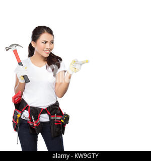 Female construction worker wearing une ceinture à outils pleine d'une variété d'outils utiles et pointant vers le haut Banque D'Images