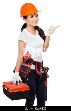 Femme portant des vêtements de travail avec toolbelt holding boîte à outils et pointant vers le haut Banque D'Images