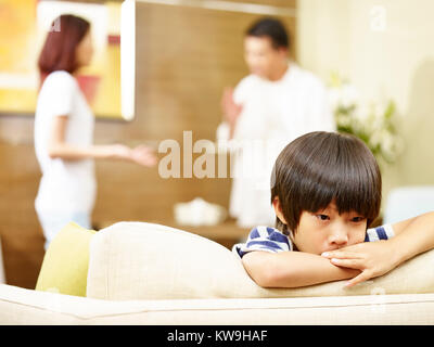 Enfant asiatique semble triste et malheureux alors que les parents se disputer à l'arrière-plan. Banque D'Images